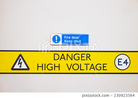 Danger High Voltage Warning Sign on White Wall - Electrical Hazard Safety Symbol Danger High Voltage Warning Sign on White Wall - Electrical Hazard Safety Symbol 130923564