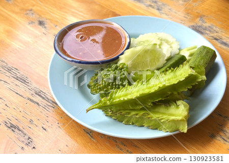 Traditional Thai food side dish, fresh and steamed vegetables and spicy salty sauce from shrimp paste and herbs - called Nam Prick in Thai language. Traditional Thai food side dish, fresh and steamed vegetables and spicy salty sauce from shrimp paste and herbs - called Nam Prick in Thai language. 130923581