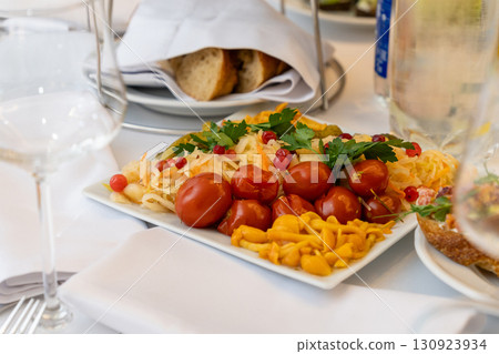 Marinated appetizers on a square white plate served on a festive holiday table Marinated appetizers on a square white plate served on a festive holiday table 130923934