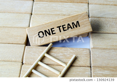 A wooden block engraved with ONE TEAM on stairs concept representing unity, partnership, collaboration and cooperation. A wooden block engraved with ONE TEAM on stairs concept representing unity, partnership, collaboration and cooperation. 130924139