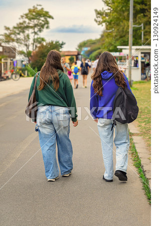 Two teenage girls walking side by side down a street in casual hoodies and baggy jeans. Concept of youth lifestyle, street fashion, teenage friendship Two teenage girls walking side by side down a street in casual hoodies and baggy jeans. Concept of youth lifestyle, street fashion, teenage friendship 130924149