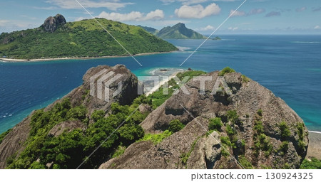 Fiji, Kuata island: green tropical islands rise majestically from turquoise water of a tranquil ocean, creating a breathtaking panorama of natural beauty. Low drone flight over rock cliffs 130924325