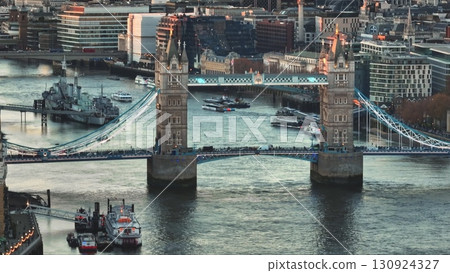 United Kingdom, London: Aerial view of Tower Bridge at sunset over River Thames with boats sailing and HMS Belfast docked, in London, United Kingdom. Drone flight 130924327