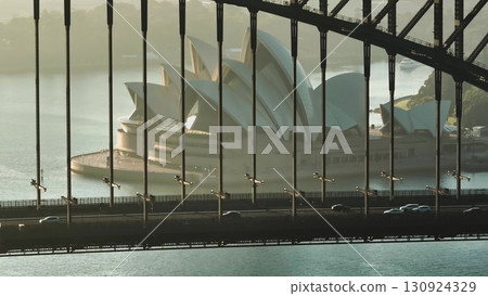 Australia, Sydney City: Sydney Harbour Bridge at sunrise, with Sydney Opera House framed between the bridge's girders. Cars driving traffic road. Modern architecture and urban transport in Australia 130924329