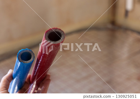 Red and blue pipes of the water supply and heating system. Closeup, selective focus. Red and blue pipes of the water supply and heating system. Closeup, selective focus. 130925051