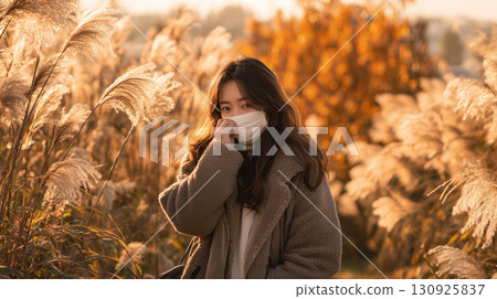 Japanese pampas grass swaying in the autumn breeze and a woman wearing a mask 130925837
