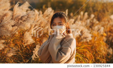 Japanese pampas grass swaying in the autumn breeze and a woman wearing a mask 130925844