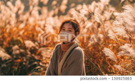 Japanese pampas grass swaying in the autumn breeze and a woman wearing a mask 130925863