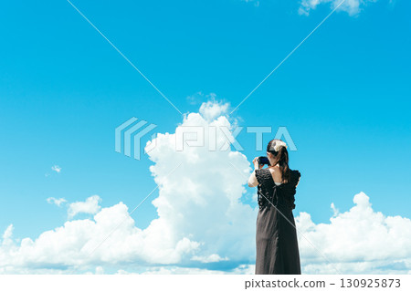 Back view of a woman holding a camera under the blue sky 130925873