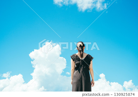 Back view of a woman looking up at the blue sky 130925874