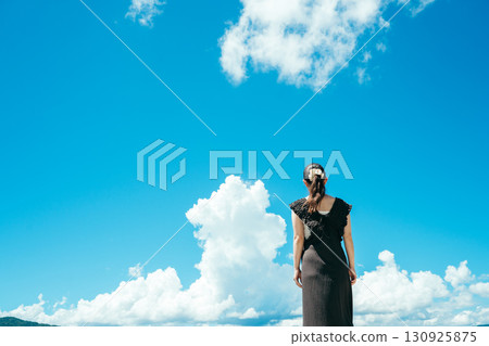 Back view of a woman looking up at the blue sky 130925875
