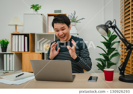surprised man working with laptop computer at home office 130926293