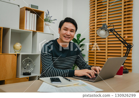 happy man working with laptop computer at home office happy man working with laptop computer at home office 130926299