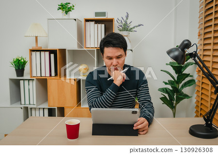 man thinking while using digital tablet at home office man thinking while using digital tablet at home office 130926308