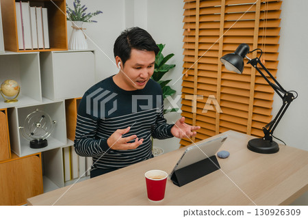stressed man using digital tablet and wireless earbuds making video call in home office stressed man using digital tablet and wireless earbuds making video call in home office 130926309