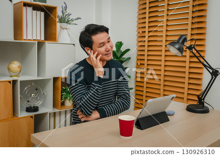 happy man using wireless earbuds to listening music and tablet at home office happy man using wireless earbuds to listening music and tablet at home office 130926310