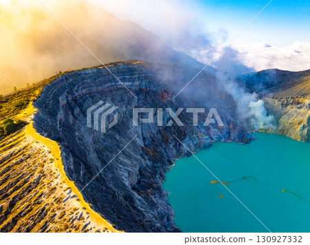 Aerial view of rock cliff at Kawah Ijen volcano with turquoise sulfur water lake at sunrise.Amazing nature landscape view at East Java, Indonesia. Natural landscape background Aerial view of rock cliff at Kawah Ijen volcano with turquoise sulfur water lake at sunrise.Amazing nature landscape view at East Java, Indonesia. Natural landscape background 130927332