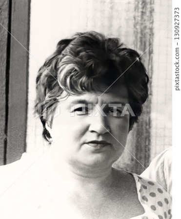A vintage portrait of a beautiful woman in her fifties. Gray hair is appearing. Retro photo from 1989. A vintage portrait of a beautiful woman in her fifties. Gray hair is appearing. Retro photo from 1989. 130927373