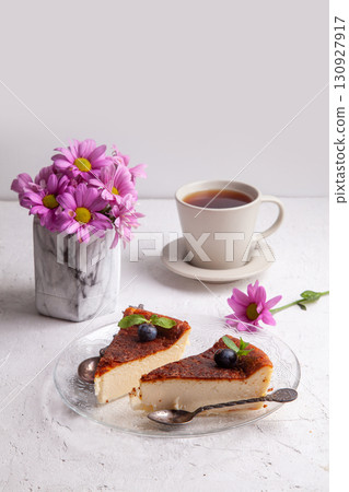 Slices of Homemade Basque burnt cheesecake on a plate with blueberries and mint leaves on light background 130927917
