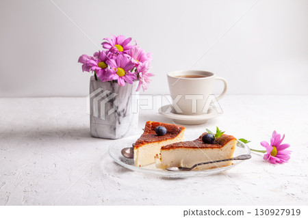 Slices of Homemade Basque burnt cheesecake on a plate with blueberries and mint leaves on light background Slices of Homemade Basque burnt cheesecake on a plate with blueberries and mint leaves on light background 130927919