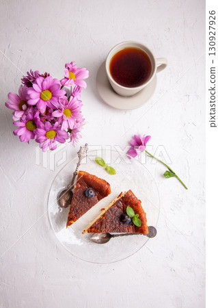 Slices of Homemade Basque burnt cheesecake on a plate with blueberries and mint leaves on light background 130927926