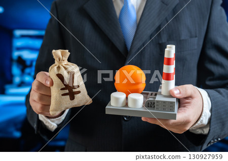 Yen or yuan money bag and chemical plant in the hands of a businessman. Investments in the energy or chemical sector. Symbol of petrochemicals, trade, finance, taxes, and economy. 130927959
