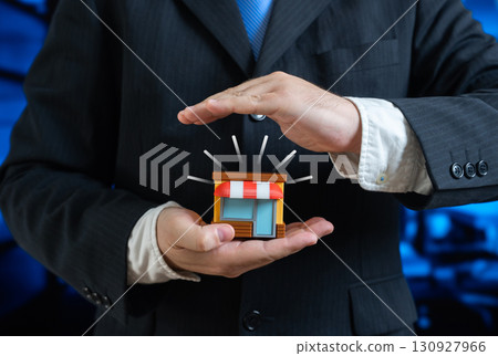 A man holds a small shop in his hands. Protect your business and keep it for development. Business insurance. Support for entrepreneurship and retail trade security. 130927966