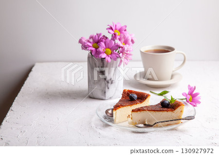 Slices of Homemade Basque burnt cheesecake on a plate with blueberries and mint leaves on light background Slices of Homemade Basque burnt cheesecake on a plate with blueberries and mint leaves on light background 130927972
