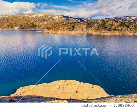Panoramic view of the valley with mountain lake. Lake Svartavatnet in the mountains in summer. Natural park in the municipality of Sauda. The beautiful nature of Norway Panoramic view of the valley with mountain lake. Lake Svartavatnet in the mountains in summer. Natural park in the municipality of Sauda. The beautiful nature of Norway 130928460