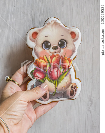 Hand holDecorated gingerbread bear cookie holding flowers in human hand. Cute homemade pastry, sweet festive dessert, creative holiday treat.ding gingerbread cookie shaped like a bear with flowers Hand holDecorated gingerbread bear cookie holding flowers in human hand. Cute homemade pastry, sweet festive dessert, creative holiday treat.ding gingerbread cookie shaped like a bear with flowers 130929522