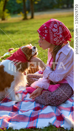 Girl in red bandana sitting on blanket with dog in matching accessory and sunglasses Girl in red bandana sitting on blanket with dog in matching accessory and sunglasses 130929750