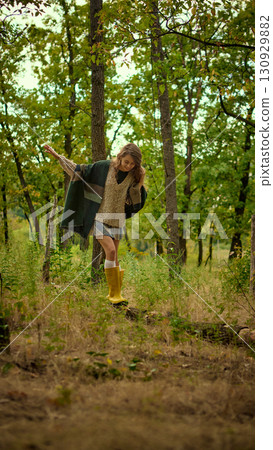 Woman balancing on forest path in autumn outfit and yellow boots Woman balancing on forest path in autumn outfit and yellow boots 130929882