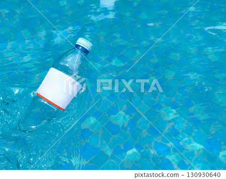 Plastic bottle floating on clear blue water, symbolizing pollution and environmental issues in aquatic environments. Plastic bottle floating on clear blue water, symbolizing pollution and environmental issues in aquatic environments. 130930640