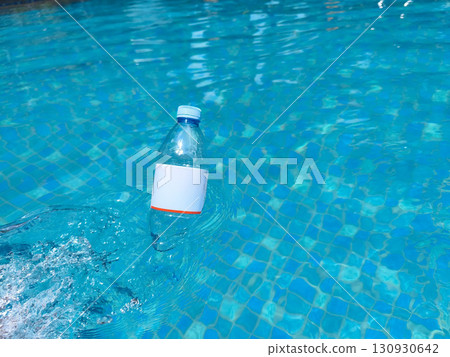 Plastic bottle floating on clear blue water, symbolizing pollution and environmental issues in aquatic environments. Plastic bottle floating on clear blue water, symbolizing pollution and environmental issues in aquatic environments. 130930642