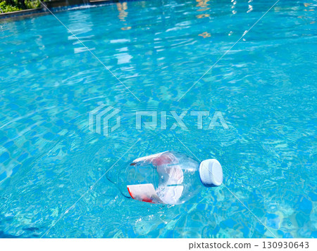 Plastic bottle floating on clear blue water, symbolizing pollution and environmental issues in aquatic environments. 130930643