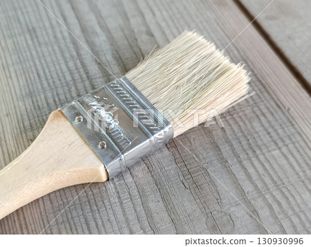 A paint brush lies on a wooden surface A paint brush lies on a wooden surface 130930996