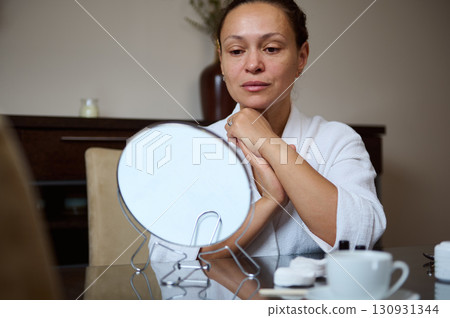 Woman Contemplating Before a Mirror in a Relaxed Indoor Setting 130931344