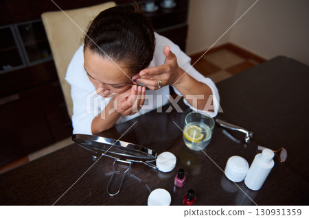 Woman Performing Skincare Routine at Home with Makeup Products 130931359