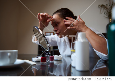 Woman Performing Skincare Routine in Front of a Mirror at Home Woman Performing Skincare Routine in Front of a Mirror at Home 130931360