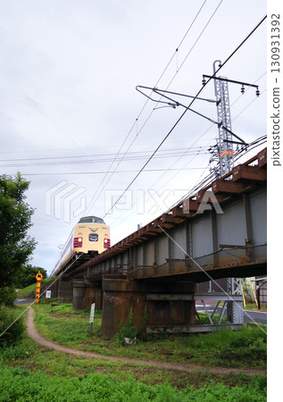 A 381 series Yakumo express train, painted in the old JNR colors as part of a revival project, passes through a low-profile iron bridge in the city. A 381 series Yakumo express train, painted in the old JNR colors as part of a revival project, passes through a low-profile iron bridge in the city. 130931392
