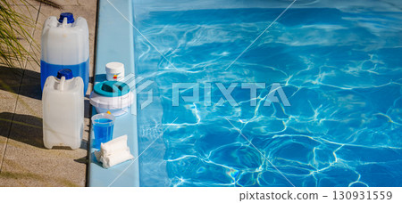 Poolside cleaning kit with blue chemical canisters, chlorine tablets, floating dispenser, measuring cup and sanitizer supplies for swimming pool maintenance 130931559