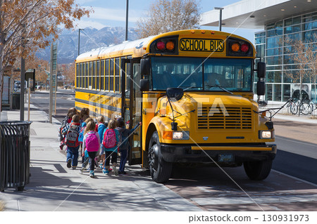 A group of elementary school children board a yellow school bus. A group of elementary school children board a yellow school bus. 130931973