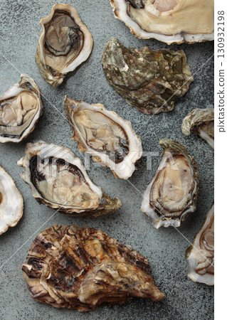 Fresh opened oysters scattered on dark gray surface top view 130932198