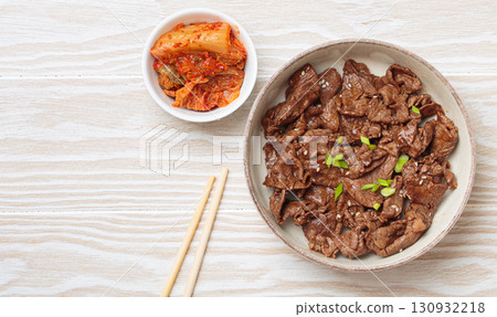 Bulgogi, grilled marinated beef Korean dish with kimchi and sesame seeds top view on white wooden background Bulgogi, grilled marinated beef Korean dish with kimchi and sesame seeds top view on white wooden background 130932218