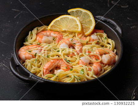 Delicious seafood pasta spaghetti with shrimps dish garnished with lemon and parsley anglr view on black background Delicious seafood pasta spaghetti with shrimps dish garnished with lemon and parsley anglr view on black background 130932225