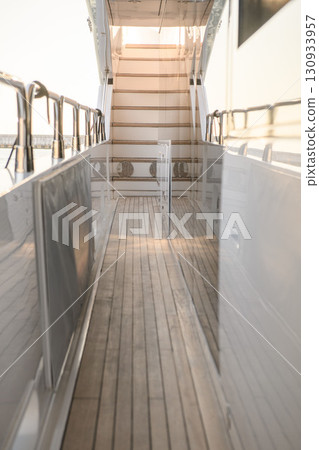 Side deck of a luxury yacht with wooden flooring and stairway view 130933957