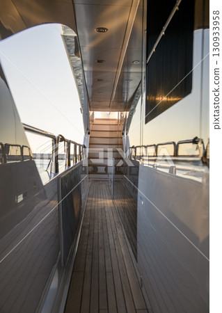 Side deck of a luxury yacht with wooden flooring and stairway view 130933958