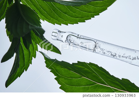 A pipette with serum in mint leaves. A pipette with serum in mint leaves. 130933963