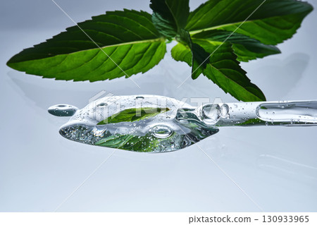 A pipette with serum in mint leaves. 130933965