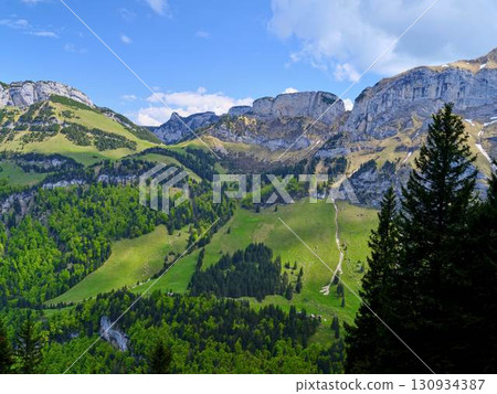 Mountains and lush greenery create a serene landscape under a bright blue sky in early afternoon 130934387